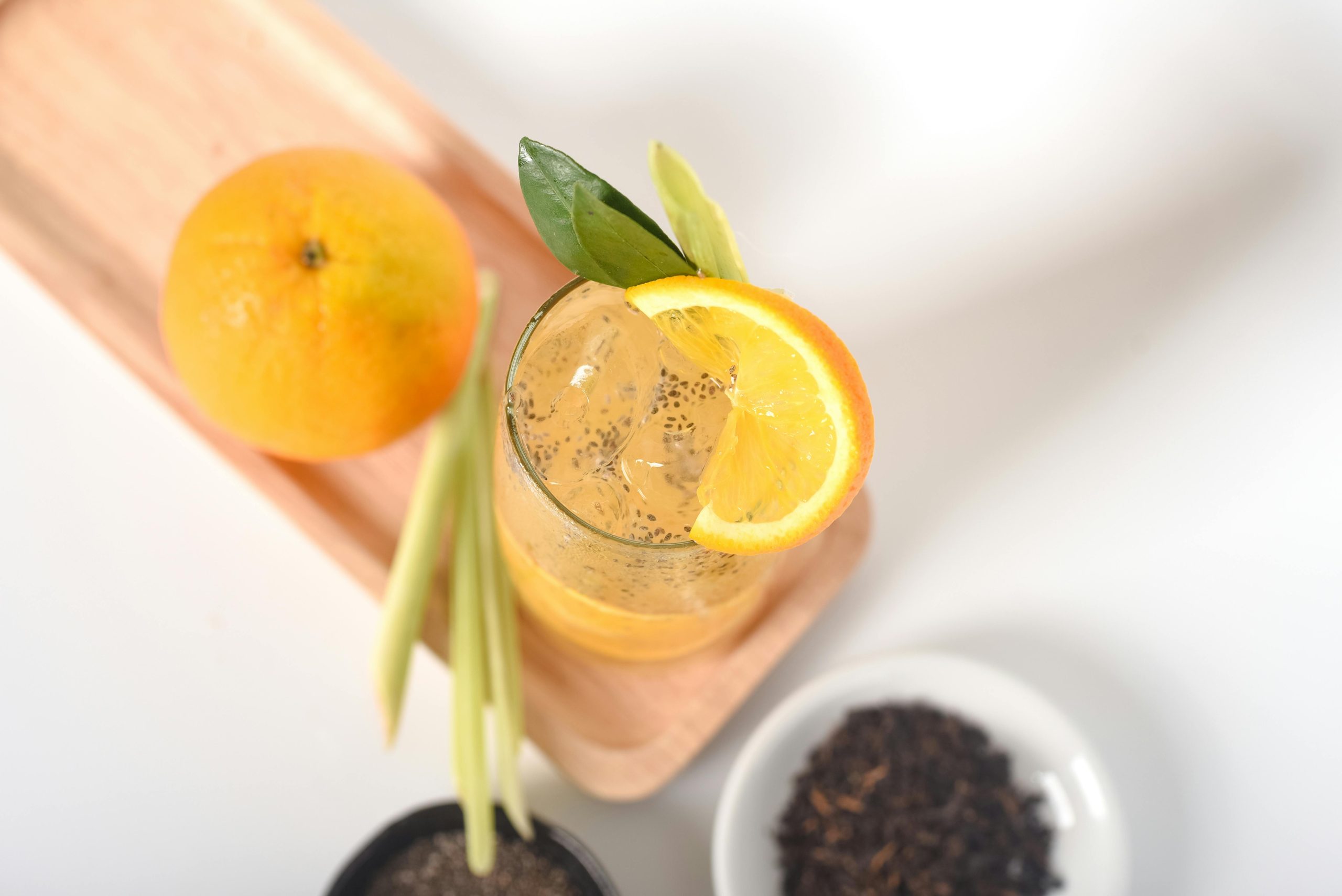 Close-up of a refreshing orange juice with lemongrass and chia seeds in bright setting.